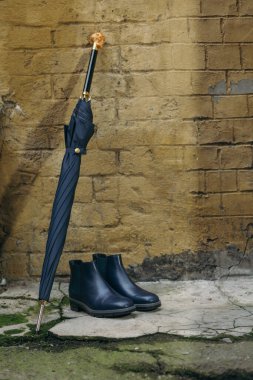 Sokakta şemsiyeli ve bastonlu erkek ayakkabıları var.