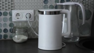 Ev aletleri, masadaki şeffaf cam çaydanlıkta yüksek ısıdan dolayı saf su kaynıyor..