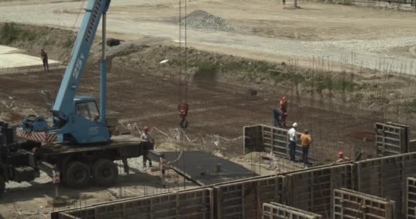 Los trabajadores que trabajan en el sitio de construcción de la casa en las montañas. Construcción de grúa de carga de materiales de construcción. Maquinaria pesada en construcción. — Vídeo de stock