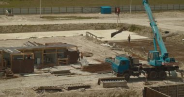 Dağlarda inşaat alanında çalışan işçiler. İnşaat vinci inşaat malzemeleri yüklüyor. İnşaatta ağır makineler.