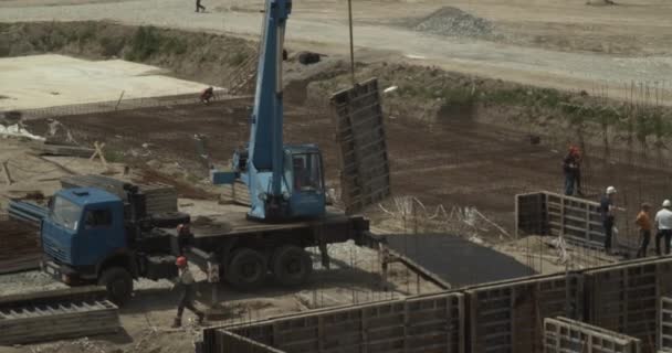 Arbetstagare som arbetar på byggarbetsplatsen avlägsnas från drönaren. Byggare bygger ett hus. — Stockvideo