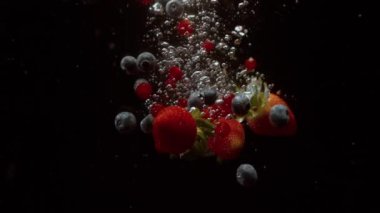 Siyah arka planda suya düşen böğürtlenler. Yüksek hızlı sinema kamerasıyla çekilmiş.,