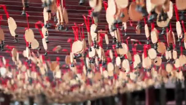 Campanas de madera con deseos cuelgan y se mueven del viento. Hainan, China. Abróchate. Campanas en cintas rojas — Vídeos de Stock