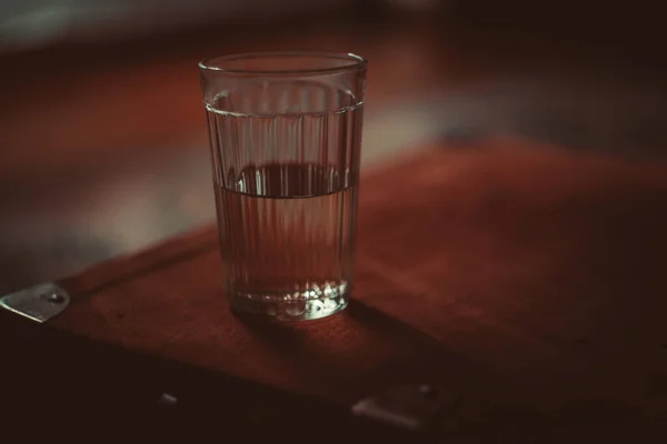 Gezond houden en gehydrateerd blijven met een glas ijswater thuis of restaurant op wazige achtergrond van groene eettafel en houten stoel. — Stockfoto