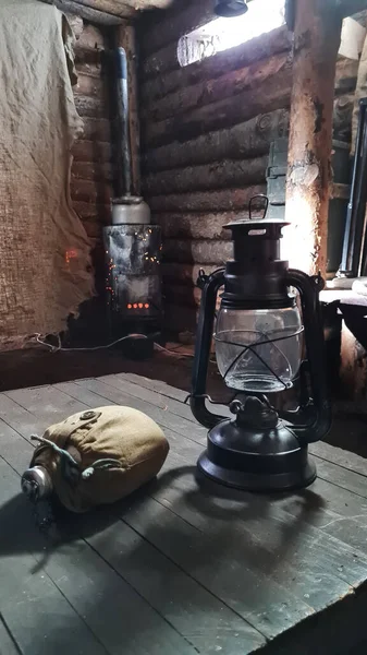Ένα ξύλινο πάπλωμα στο οποίο καίγεται μια λάμπα κηροζίνης. Φως από το παράθυρο διεισδύει στο δωμάτιο. — Φωτογραφία Αρχείου