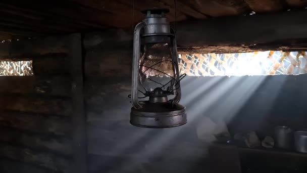 A wooden dugout in which a kerosene lamp burns. Light from the window penetrates into the room. — Stock Video