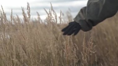 Bir kadının eli çimenleri okşuyor. Kadın ve erkek eve doğru yürüyorlar.