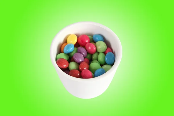 White Jar full of multicolored candies on green gradient — Stock Photo, Image