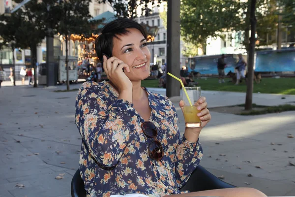 La mujer bebe el jugo y habla por teléfono. — Foto de Stock