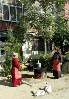 Ashgabat, Turkmenistan - Circa October  2021: Women prepare food (pilaf) on the street in 2 large cauldrons for the wedding clipart