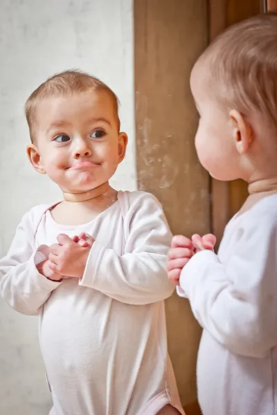 Baby standing against the mirror — Stock Photo, Image