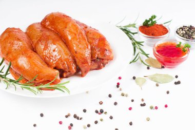 Taze biberiye yaprakları ve baharatlarla birlikte beyaz bir tabakta kırmızı soslu çiğ tavuk filetosu. Taze marine edilmiş tavuk eti..