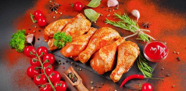 Biberiye yaprakları, taze kiraz domatesleri ve çeşitli baharatlarla birlikte, siyah bir yemek tahtasında marine edilmiş ızgara tavuk çorbası. Yakın plan, yarı bitmiş ürün, marine edilmiş ürün, hızlı pişirme..