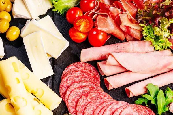 Şarküteri, salam, peynir, camembert ve zeytin içeren antipasti tabağı. Ahşap masa üzerinde çeşitli et ve sosisler. Peynirli Antipasto tabağı..