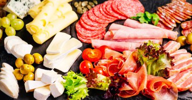 Şarküteri, salam, peynir, camembert ve zeytin içeren antipasti tabağı. Ahşap masa üzerinde çeşitli et ve sosisler. Peynirli Antipasto tabağı..