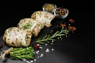 Çiğ et tavuğu. Çiğ tavuk budu. Bitki sosuyla marine edilmiş. Arka planda taze biberiye ve baharatlar var. Baharatlı tavuk budu, sarımsak. Boşluğu kopyala..