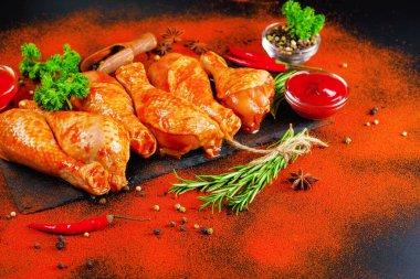 Uygun yemek, önceden pişirilmiş. Baharatlı çiğ tavuk eti bacağı ve barbekü koyu arkaplan için pişirme. Üst görünüm. Boşluğu kopyala.