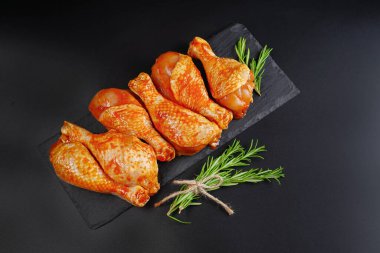 Uygun yemek, önceden pişirilmiş. Baharatlı çiğ tavuk eti bacağı ve barbekü koyu arkaplan için pişirme. Üst görünüm. Boşluğu kopyala.