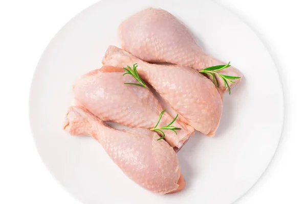 Świeże nogi kurczaka zbliżenie izolatę.Widok z góry cztery-częściowy surowy cały udko kurczaka na białym talerzu na białym odizolowanym tle. — Zdjęcie stockowe