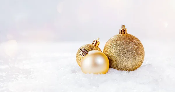 Una varietà di palline di Natale lucido dorato sulla neve su uno sfondo leggero.Natale e Capodanno Glitter, sfondo lucido.Natale, inverno, nuovo anno concettuale.decorazioni per la casa.. — Foto Stock