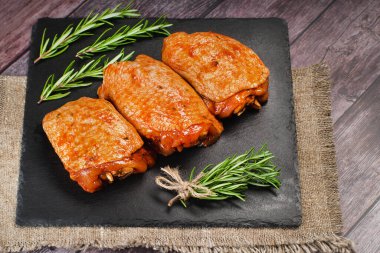 Kırmızı soslu tavuk butları biberiye yapraklı mutfak seramik tahtasında terbiye edildi. Çiğ tavuk eti..