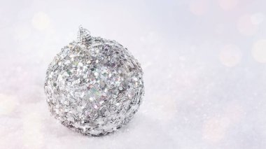 Hafif arka planda parlak, gümüş cam bir Noel topu. Işıltılı, parlak arka plan. Noel, kış, yeni yıl konsepti. Kopya alanı. Kış Arkaplanı..