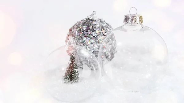 Olika julen glasbollar på snön på en ljus bakgrund. Närbild .Jul, vinter, nytt år koncept.Gratulationskort, banderoll, affisch.Julen glasboll med en miniatyr julgran. — Stockfoto