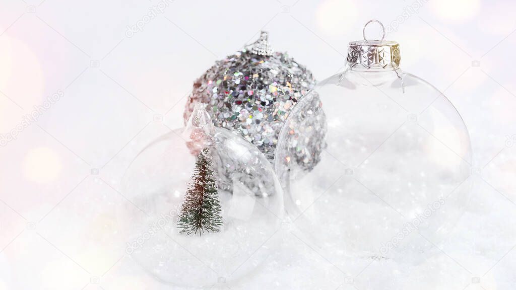 Various Christmas glass balls on the snow on a light background. Close-up .Christmas, winter, new year concept.Greeting card, banner, poster.Christmas glass ball with a miniature Christmas tree.