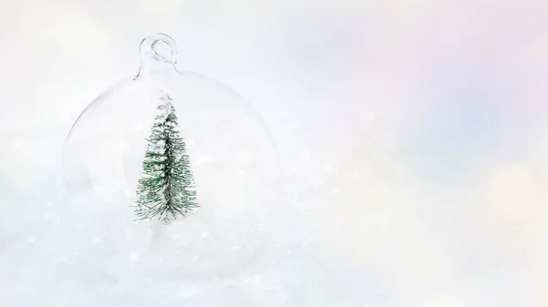 Morbido fuoco.Lucido, palla di Natale in vetro con un albero di Natale in miniatura sulla neve su uno sfondo chiaro.Composizione natalizia.Sfondo lucido.copia spazio.Biglietto di auguri, banner, poster. — Foto Stock