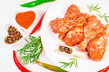 Kırmızı soslu terbiye edilmiş tavuk çubuğu beyaz bir tabakta baharat ve sebzelerle. BBQ davul çubuğu. Yarı bitti. Hızlı pişirme. Çiğ terbiye edilmiş tavuk eti, tavuk bacağı..