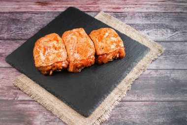 Kırmızı sosla marine edilmiş çiğ tavuk butları. Yarı pişmiş tavuk butları. Manzaralı. Çiğ tavuk marine edildi. Boşluğu kopyala.