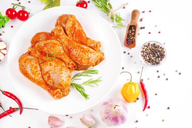 Barbekü soslu tavuk dramsticks siyah mutfak tahtası, taze biberiye yapraklı beyaz arka plan ve kiraz domatesleri, çeşitli baharatlar, yakın plan. Yarı bitmiş ürün, çabuk pişirme..