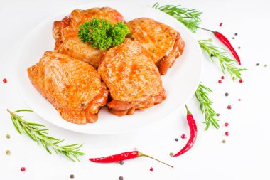 Çiğ tavuk butları kırmızı sosla marine edilmiş beyaz tabakta, beyaz tabakta taze biberiye ve kırmızı acı biberle. Yarı pişmiş tavuk butları. Manzaralı. Çiğ tavuk marine edildi..