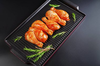 Uygun yemek, önceden pişirilmiş. Baharatlı çiğ tavuk eti bacağı ve barbekü koyu arkaplan için pişirme. Üst görünüm. Boşluğu kopyala.