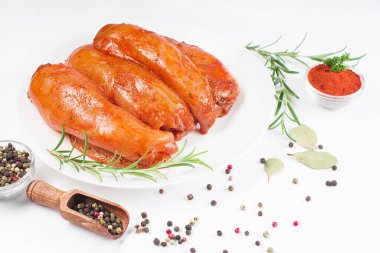 Taze biberiye yaprakları ve baharatlarla birlikte beyaz bir tabakta kırmızı soslu çiğ tavuk filetosu. Taze marine edilmiş tavuk eti..