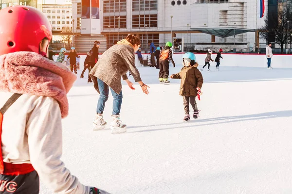 Slovakia.Bratislava.28.12.2018 .Enjoying winter outdoor activities.Winter sport.People ice skating on the City Park Ice Rink Adorable little kisd in winter clothes with protections skating on ice rink — Foto Stock