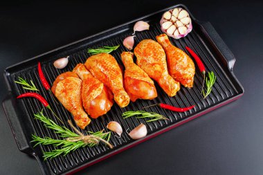 Uygun yemek, önceden pişirilmiş. Baharatlı çiğ tavuk eti bacağı ve barbekü koyu arkaplan için pişirme. Üst görünüm. Boşluğu kopyala.