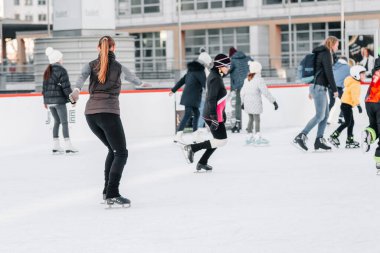 Yumuşak, seçici odaklanma. İnsanlar, dostluk, spor ve eğlence kavramı - mutlu arkadaşlar buz pistinde kayıyor. Bir grup genç arkadaş buz pateni yapıyor..