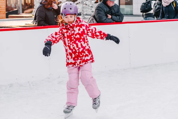 Zacht, selectief focus.Schattig klein klokje in winterkleding met bescherming schaatsen op ijsbaan.Een kind van 3-5 jaar oud, leren trein, rijden wintersportbaan, schaatsen.Buiten.Wintersport. — Stockfoto