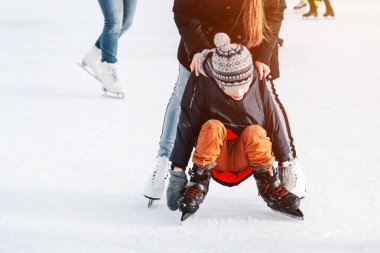 Yumuşak, seçici odaklanma. 6 yaşında bir çocukla anne, tren öğrenme, kış kenti buz pateni pistine binme, buz pateni. Çocuk kalkar, paten kayar, diz çöker, hafta sonları dinlenir.