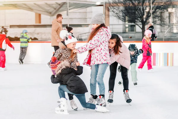 Soft,Selective focus.People, friendship, sport and leisure concept - happy friends on skating rink.Group of teenage friends ice skating on an ice rink.Funny moment fell on the ice skating rink. — Stock Photo, Image