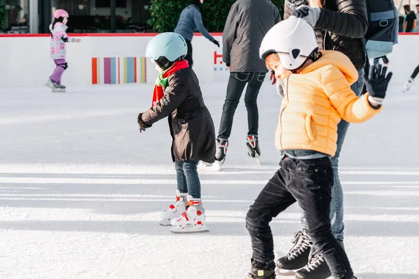 Slovakia.Bratislava.28.12.2018 .Soft,Selective focus.People ice skating on the City Park Ice Rink Adorable little kisd in winter clothes with protections skating on ice rink — Stok Foto