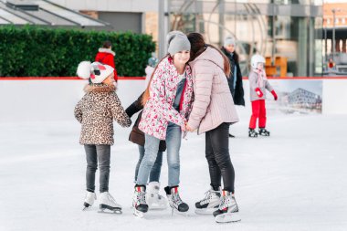 Yumuşak, seçici odaklanma. İnsanlar, arkadaşlık, spor ve eğlence kavramı - mutlu arkadaşlar buz pistinde kayıyor. Bir grup genç arkadaş buz pateni yaparken dinleniyor..