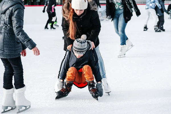 Yumuşak, seçici odaklanma. 6 yaşında bir çocukla anne, tren öğrenme, kış kenti buz pateni pistine binme, buz pateni. Çocuk kalkar, paten kayar, diz çöker, hafta sonları dinlenir..