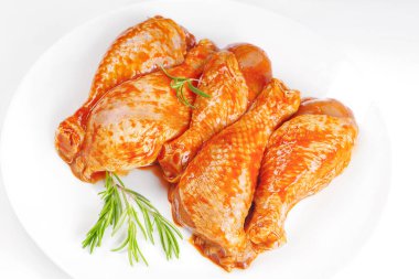 Baner. Tavuk budu pişiriyorum. Arka planda biberiyeli marinada çiğ tavuk budu. Pişirmek için baharatlı tavuk budu.