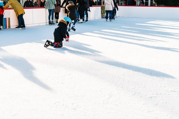 Concentration douce et sélective. enfant est tombé sur la patinoire pendant le patinage.Adorable petit bisou en vêtements d'hiver avec des protections patiner sur la patinoire. Garçon tombant pendant le patin à glace. Loisirs et loisirs. Hiver — Photo