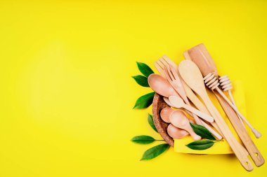 Bambu ahşap ve kağıttan yapılmış çevre dostu tek kullanımlık çatal, çatal, bıçak, bambu kaseleri ve diğerleri. Sarı arka planda basılmış bir kağıt tabakta tek kullanımlık çatal bıçak..