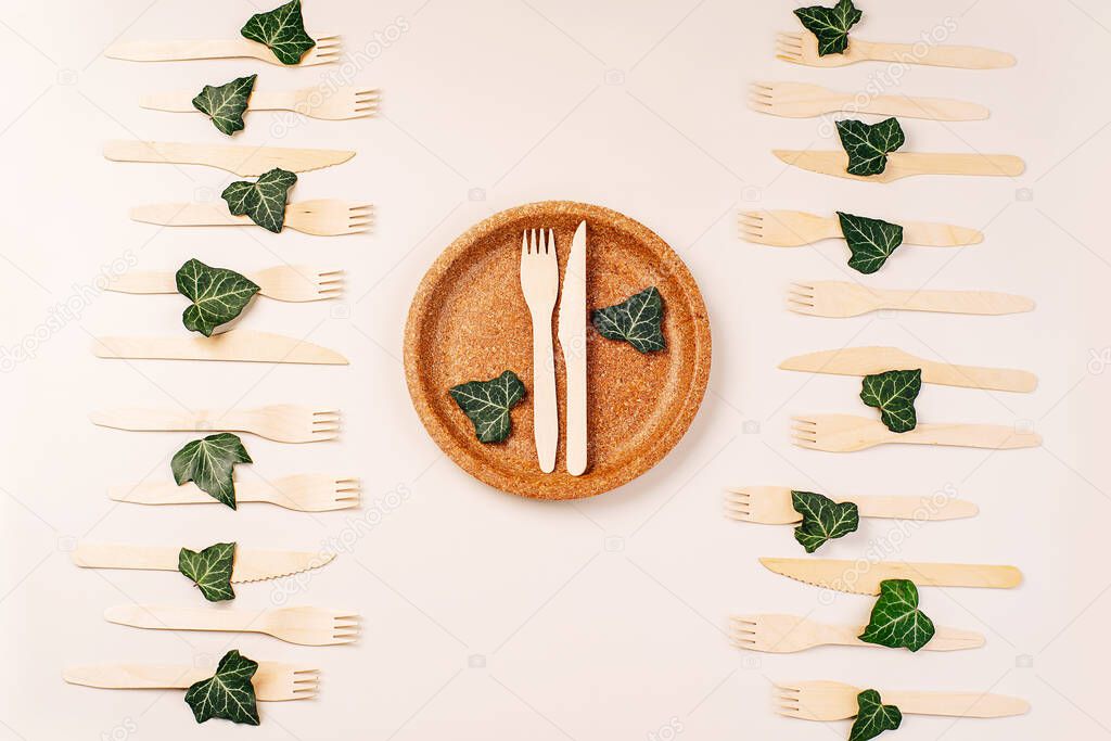 Recycling concept.Disposable cutlery on a pressed paper plate on a background.Eco-friendly disposable utensils made of bamboo wood and paper Draped spoons, fork, knives, bamboo bowls and other.
