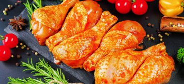 Biberiye yaprakları, taze kiraz domatesleri ve çeşitli baharatlarla birlikte, siyah bir yemek tahtasında marine edilmiş ızgara tavuk çorbası. Yakın plan, yarı bitmiş ürün, marine edilmiş ürün, hızlı pişirme..