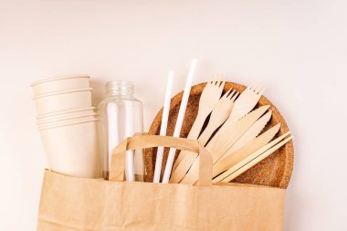 Eko-el yapımı kağıt sofra takımı, fincanlar, fast food kapları. Geri dönüşüm, çevre dostu konsept. Atılabilir eko çatal bıçak takımı, tabaklar, kaşıklar, bıçaklar, çatallar hafif bir arka planda. Yiyecek teslimatı için kağıt torba..